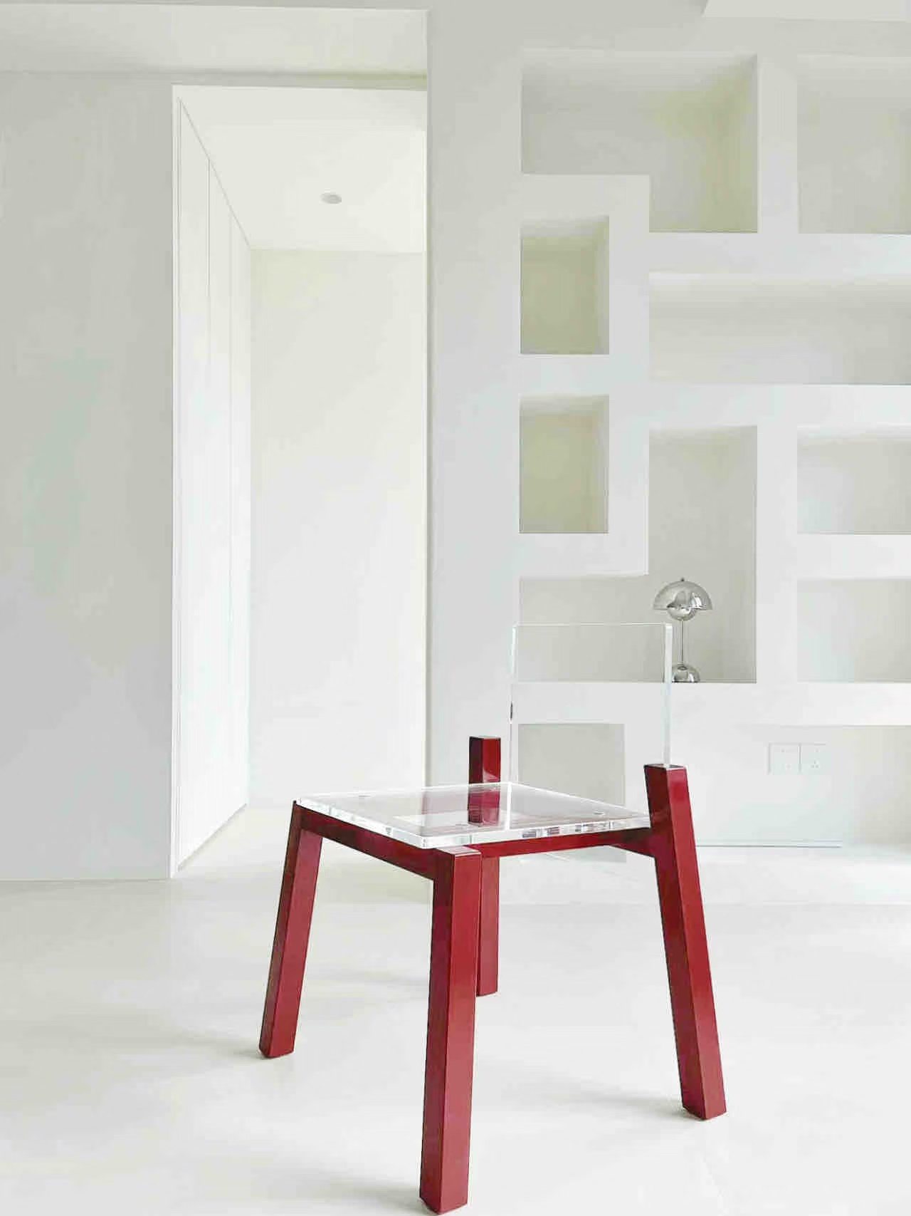 Float Chair with red legs and a clear acrylic seat in a white room